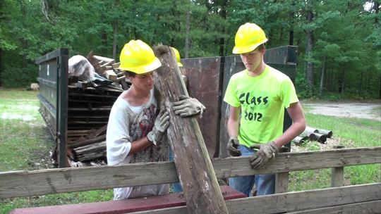 Nate Solis holding a piece of wood over a fence