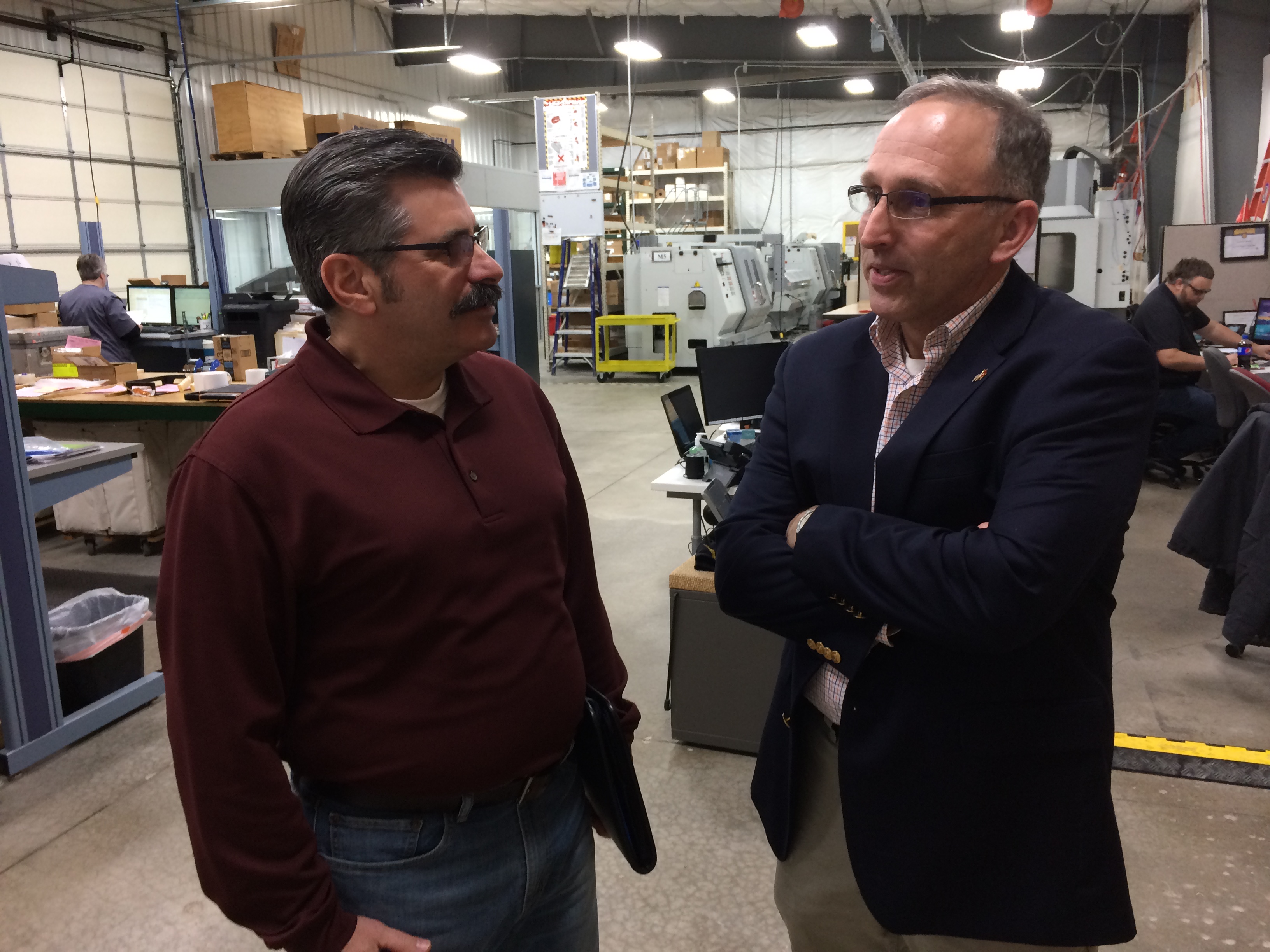 Two men standing in manufacturing area having a conversation